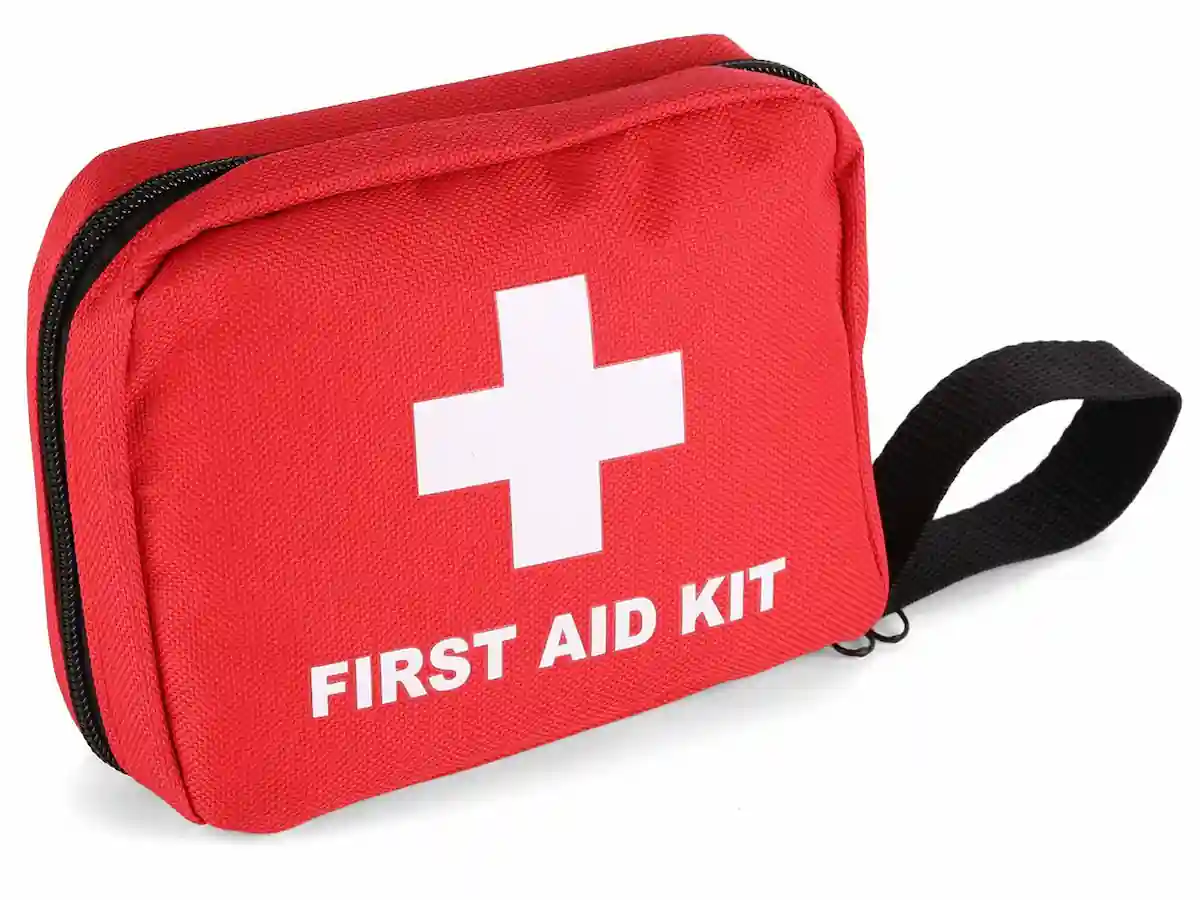 A compact red first aid kit with a white cross and the words "FIRST AID KIT" printed on the front. The kit features a black zipper closure and a black strap handle on the side for easy carrying.
