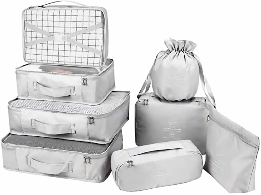 A set of light gray travel packing organizers, including various sizes of zippered cubes, a drawstring bag, and a rectangular pouch. The cubes feature mesh tops and handles for easy carrying.